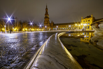 Obraz premium Plaza de España en Sevilla, Andalucía, foto nocturna con lluvia y reflejos en suelo y fuente lateral, foto con gran angular.