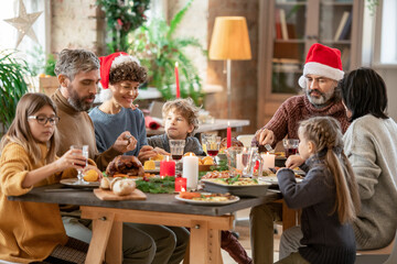 Contemporary large multi-generation family sitting by served festive table