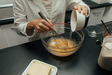 Young woman mix ingredients for making cake in kitchen.