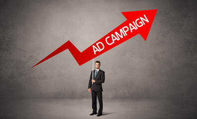 Obraz premium Young business person in casual holding road sign with AD CAMPAIGN inscription, business direction concept