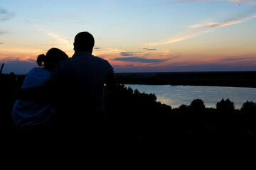 Young couple silhouette against sunset sky. Romantic evening.