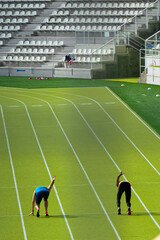 A pair of athletes rehearse the start on a green athletics track