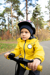 Obraz premium Active little boy in casual jacket and safety helmet riding his balance bicycle