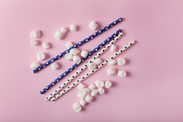 Heart-shaped lollipop and white sweet marshmallows on pink background