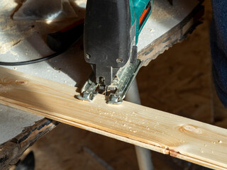 close-up of a worker sawing a wooden Board with an electric jigsaw