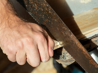 a man is sawing a board with a hand saw. Woodworking concept. Close-up