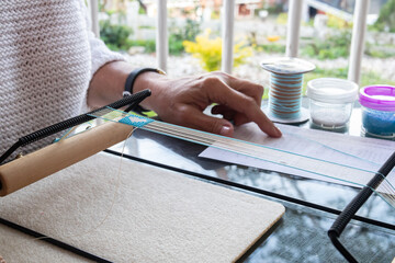 woman hands making beaded jewelry