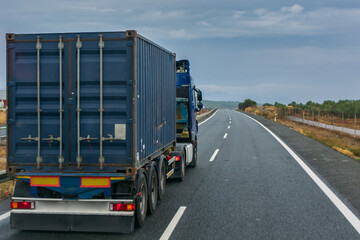 Fototapeta na wymiar Blue container truck driving on the highway on a cloudy day.
