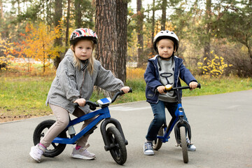 Obraz premium Two friendly little kids in casualwear and protective helmets sitting on bikes