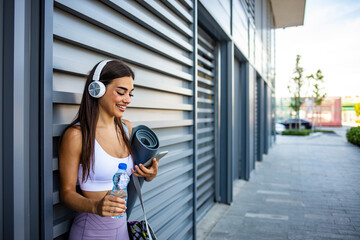 Close up portrait of an attractive young fitness woman smiling with earphones. Close up portrait of a lovely young fitness girl listening to music through wireless earphones outdoors