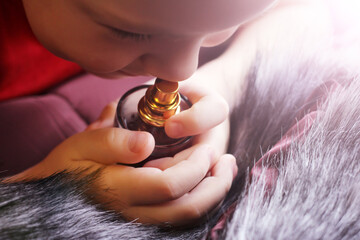 Portrait of a child with perfume, inhales the fragrance