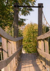 wooden bridge over the river, trees and shrubs in the background