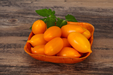 Yellow tomato heap in the wooden bowl
