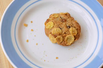 Cereal cookie in plate on wooden table. Crunchy fresh baked cookie with crumbs.