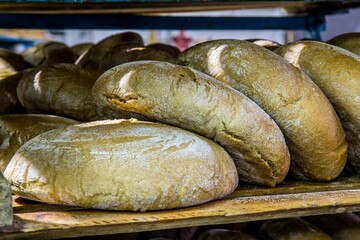Closeup of traditional round bread on the shelf. Massive production of pastry.