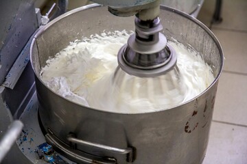 Huge bowl with white cream for cakes. Whisking process. Massive production .