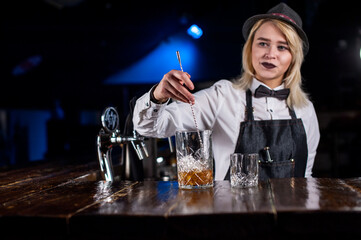 Girl barman makes a cocktail on the bar