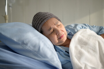 Depressed and hopeless Asian cancer patient woman wearing head scarf in hospital.