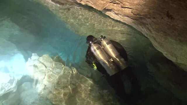 Speleodivers dive into the Orda underwater cave through a narrow underwater hole.