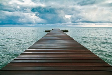 Fototapeta premium A wooden pier in blue sea and big clouds over it in Budva, Montenegro.