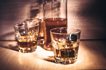 Selective focus glasses of whiskey on rustic wood background, Alcohol drink whiskey or bourbon with ice cubes on wood table together while at bar counter in the pub.