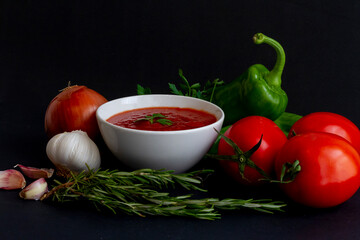 Tomato sauce in a white bowl surrounded by its ingredients: tomato of the 