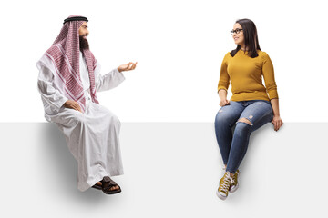 Full length profile shot of an arab man in a traditional thobe talkign to a young female and...