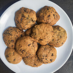 A plate of chocolate chips cookies on a brown table.
