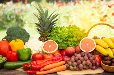 Naklejka na ściany i meble Group vegetables and Fruits Apples, grapes, oranges, and bananas in the wooden basket with carrots, tomatoes, guava, chili, eggplant, and salad on the table.Healthy food concept