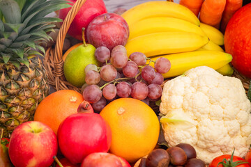 Group vegetables and Fruits Apples, grapes, oranges, and bananas in the wooden basket with carrots, tomatoes, guava, chili, eggplant, and salad on the table.Healthy food concept