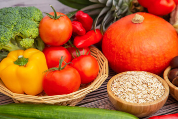 Group vegetables and Fruits Apples, grapes, oranges, and bananas in the wooden basket with carrots, tomatoes, guava, chili, eggplant, and salad on the table.Healthy food concept