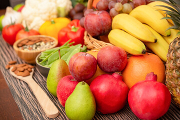 Group vegetables and Fruits Apples, grapes, oranges, and bananas in the wooden basket with carrots, tomatoes, guava, chili, eggplant, and salad on the table.Healthy food concept