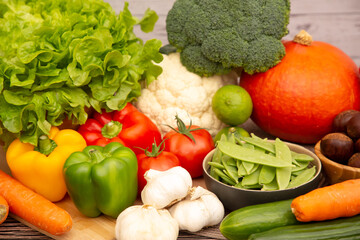 Group vegetables and Fruits Apples, grapes, oranges, and bananas in the wooden basket with carrots, tomatoes, guava, chili, eggplant, and salad on the table.Healthy food concept