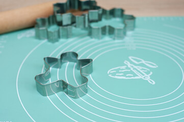 Cookie cutters and rolling pin on a silicone mat