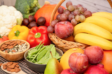 Group vegetables and Fruits Apples, grapes, oranges, and bananas in the wooden basket with carrots, tomatoes, guava, chili, eggplant, and salad on the table.Healthy food concept