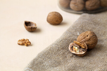 brown nuts on a light background. dried walnut on the sackcloth. close-up peeled walnuts in shells on a wooden table and in a glass jar. copy space.