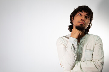 Young Hispanic man wearing casual clothes on a white background with thoughtful and pensive face