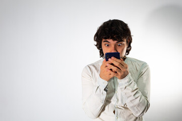 Young Hispanic man wearing casual clothes on a white background with a shocked expression
