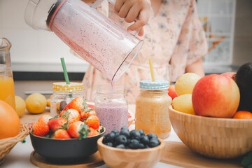 Happy woman enjoy preparing freshly squeezed fruits with vegetables for making smoothies for breakfast together in the kitchen.diet and Health concept.