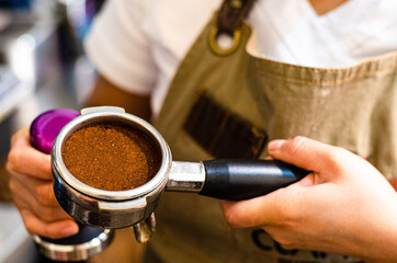 Closeup of female barista hand holding ground coffee for preparing espresso, service and preparation