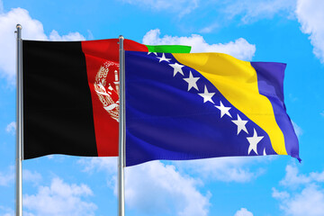 Bosnia Herzegovina and Afghanistan national flag waving in the wind on a deep blue sky together. High quality fabric. International relations concept.