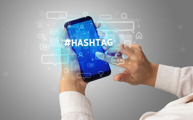 Fototapeta na wymiar Female hand typing on smartphone with #HASHTAG inscription, social media concept