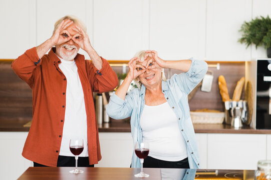 Cheerful elderly caucasian couple fooling around and having fun together at home in the kitchen