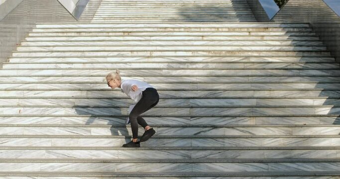 A girl manager with a tablet for papers in her hands stands on one leg, raising her hands with a report up, trying to keep her balance. An attempt to show the best result.