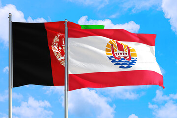 French Polynesia and Afghanistan national flag waving in the wind on a deep blue sky together. High quality fabric. International relations concept.