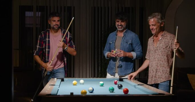 Cheerful men playing billiard while spending time together