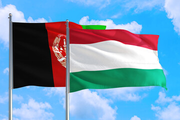 Hungary and Afghanistan national flag waving in the wind on a deep blue sky together. High quality fabric. International relations concept.