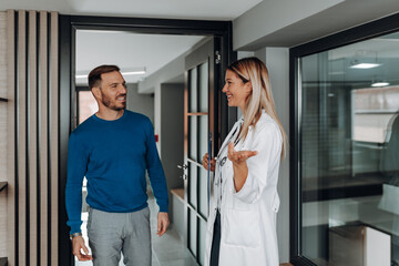 Obraz premium Doctor welcoming a male patient to her office in modern clinic.