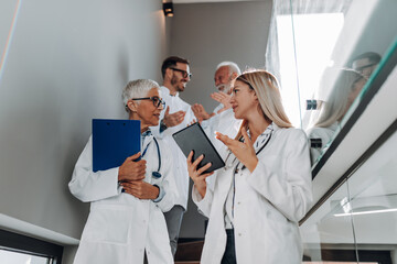 Fototapeta premium Group of doctors discussing in clinic hallway. Medical staff analyzing and working at clinic. Healthcare concept.