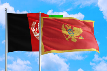 Montenegro and Afghanistan national flag waving in the wind on a deep blue sky together. High quality fabric. International relations concept.